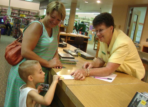 a library staff person helps a small boy at a library service desk