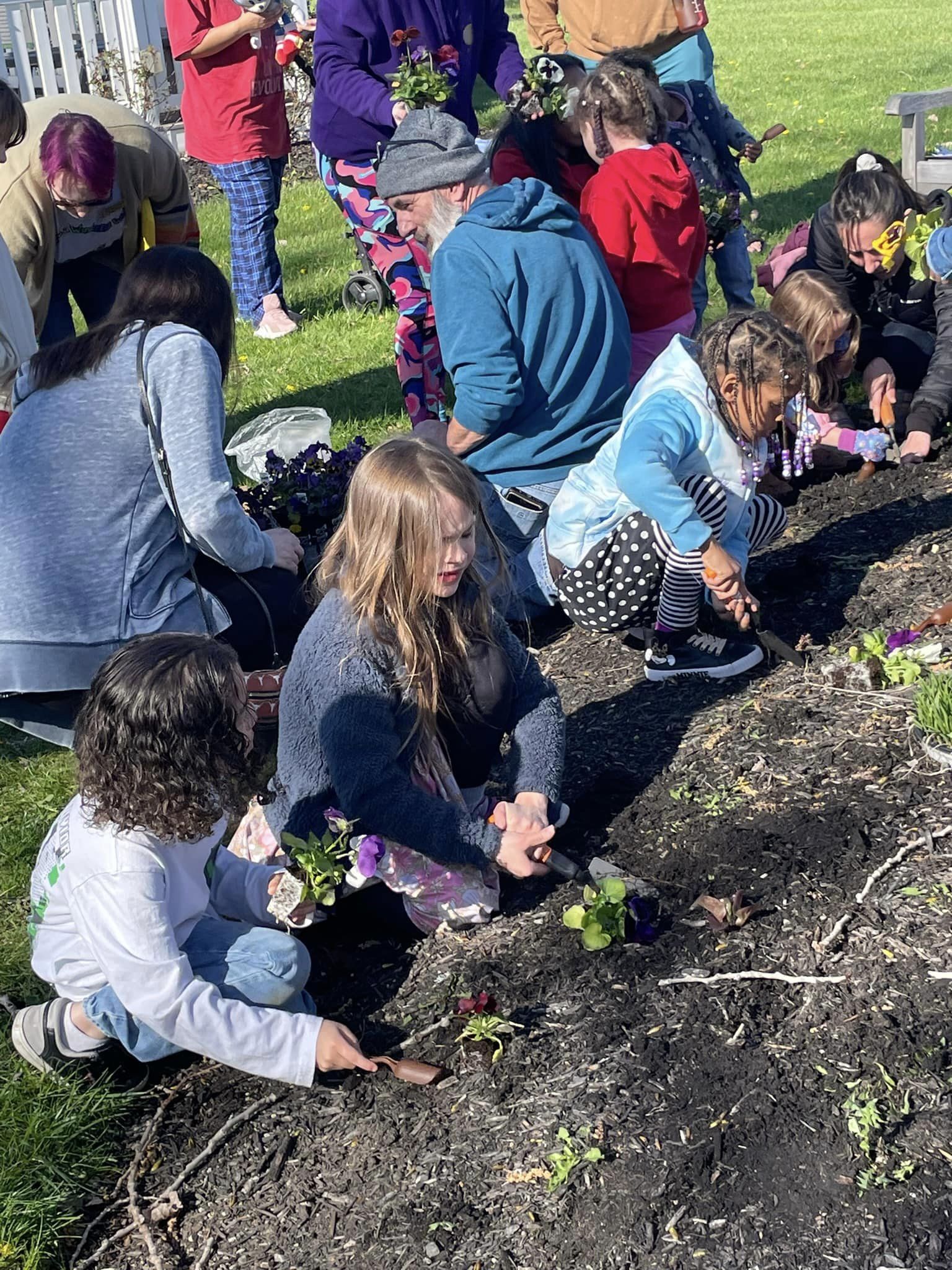 Group of children planting flowers in a bed