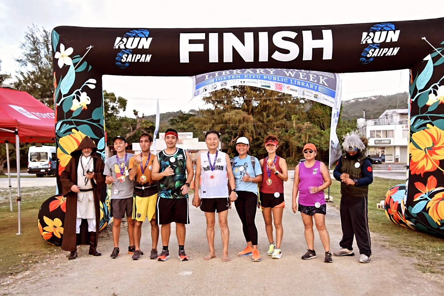 Group of smiling people standing in front of a 5k finish line