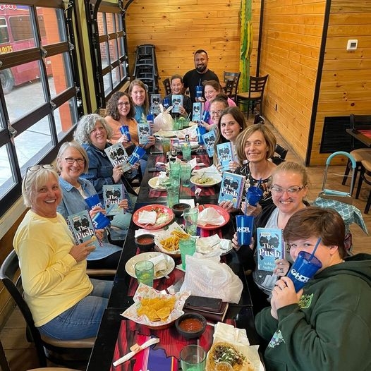 group of smiling people seated at a large restaurant table